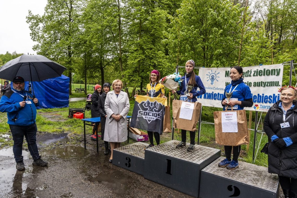 Dekoracja zwyciężczyń na podium, w tle baner kampanii o autyzmie