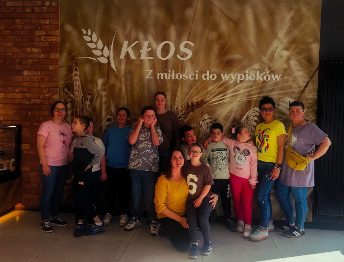 Uczniowie klas 1B, 2A i 3B z nauczycielkami przed ścianą z logo Piekarni-Cukierni Kłos