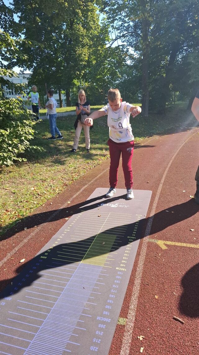 Uczeń przed skokiem w dal na macie z podziałką