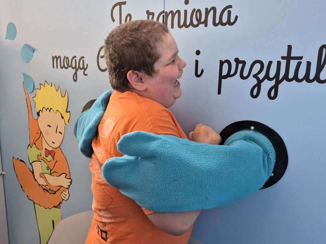 Uczeń przytulany przez miękkie ramiona instalacji