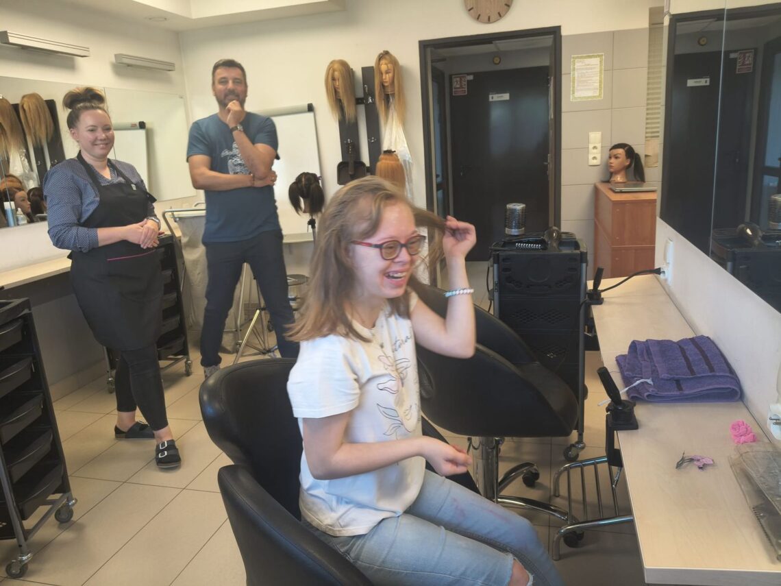 Uśmiechnięta uczennica w fotelu fryzjerskim